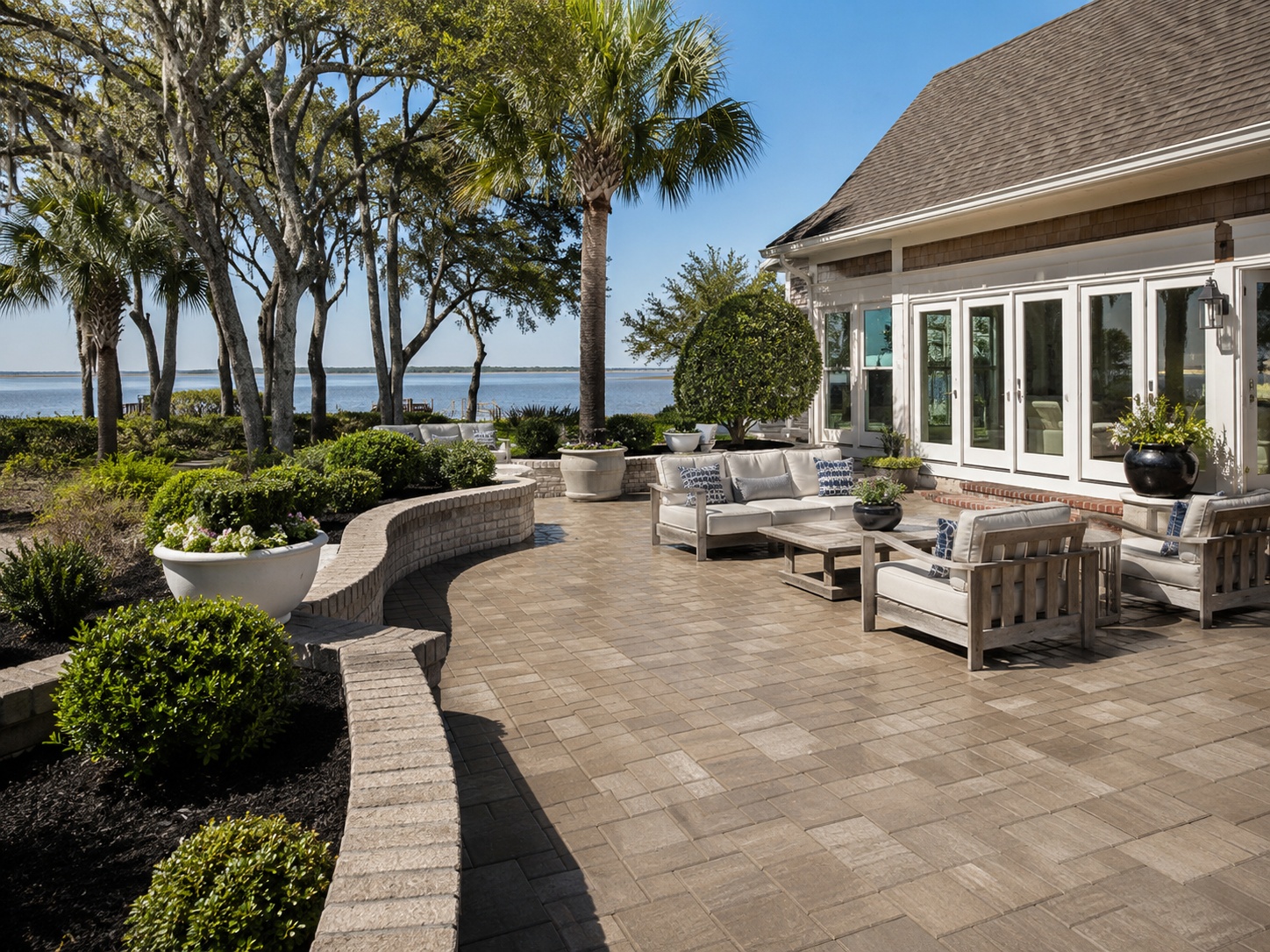 Brick patio with landscaping and mature oak trees near a home exterior
